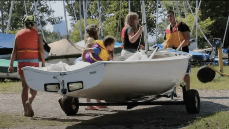 Instructor showing how to rig a sailboat to kids