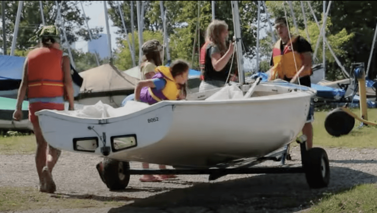 Instructor showing how to rig a sailboat to kids