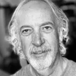 B+W headshot of a man with long curly hair