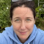 A smiling woman with dark hair in a blue shirt