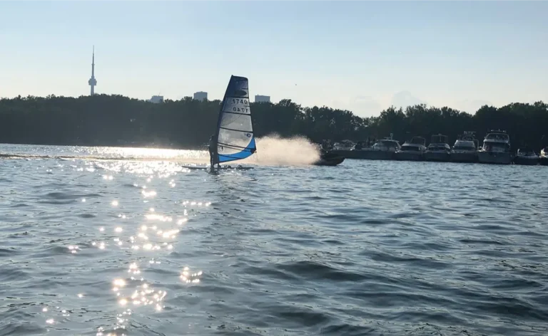 Speeding motorboat by windsurfer