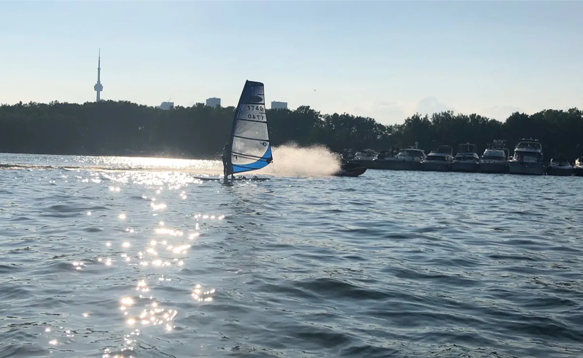 Speeding motorboat by windsurfer